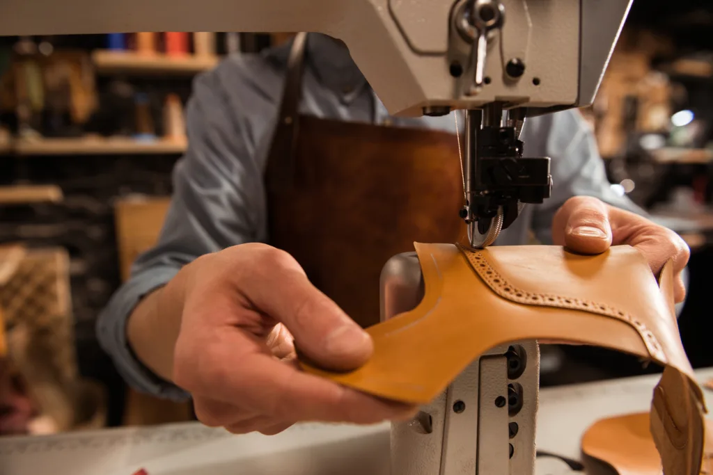 Man cobbler stitching leather patrs